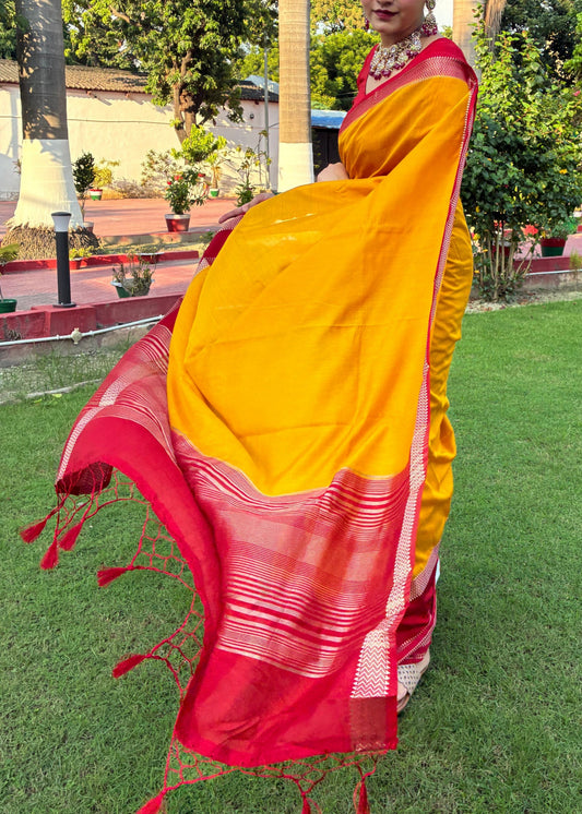 Person wearing a yellow and red saree in a park-like setting with trees and grass.
