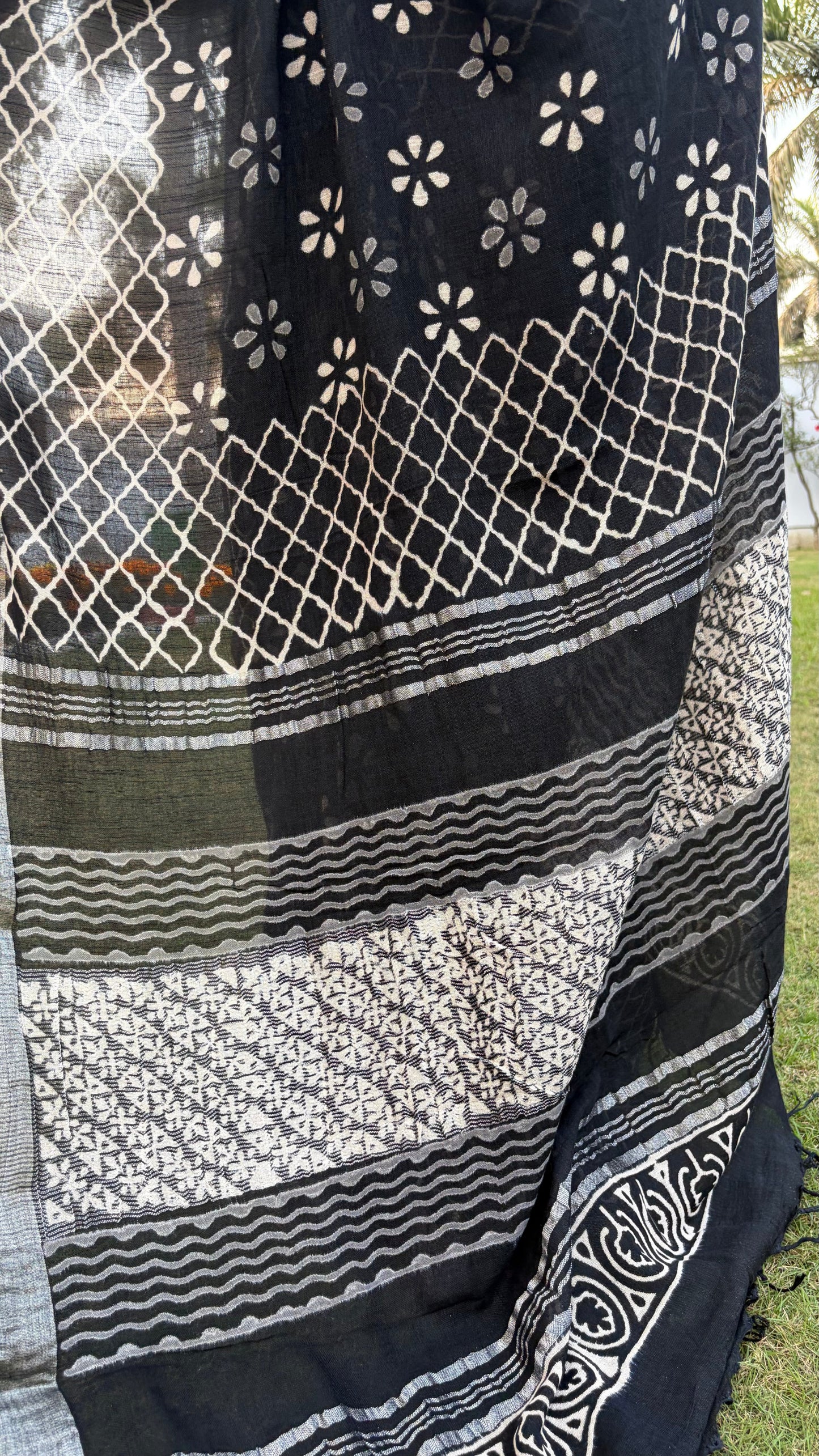 Black and white patterned fabric with geometric designs on a grassy background