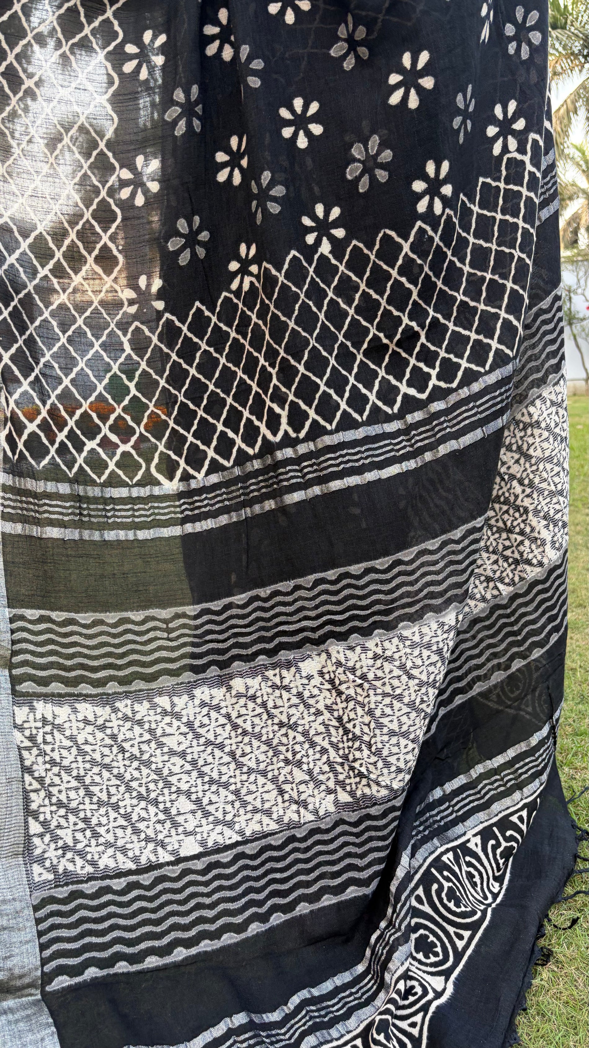 Black and white patterned fabric with geometric designs on a grassy background