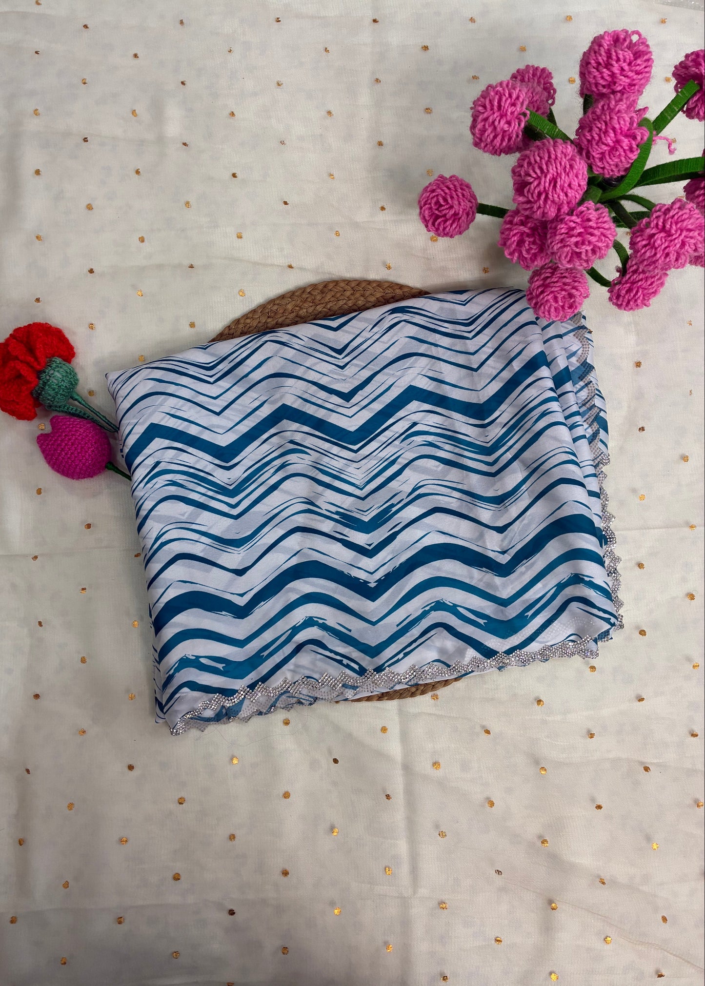 Blue and white zigzag patterned pouch with pink flowers on a textured fabric background