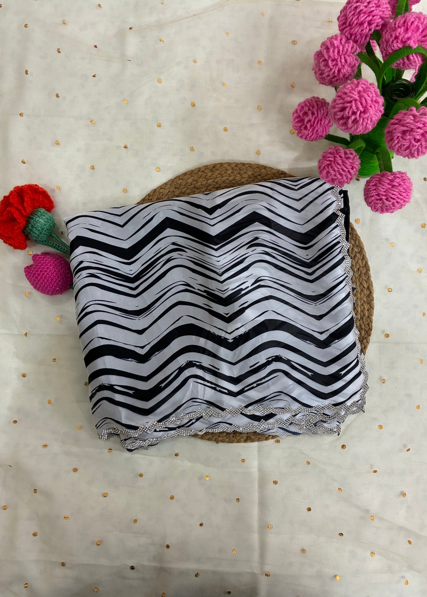 Black and white zigzag patterned fabric on a textured surface with pink and red flowers.