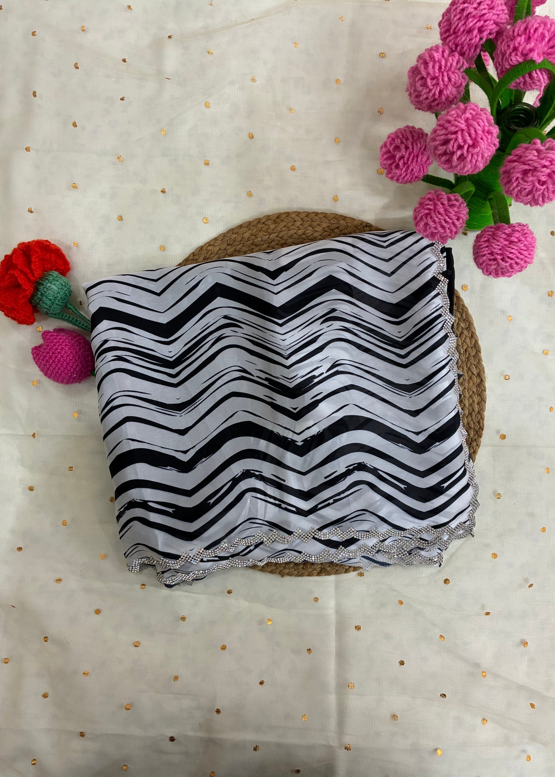 Black and white zigzag patterned fabric on a textured surface with pink and red flowers.