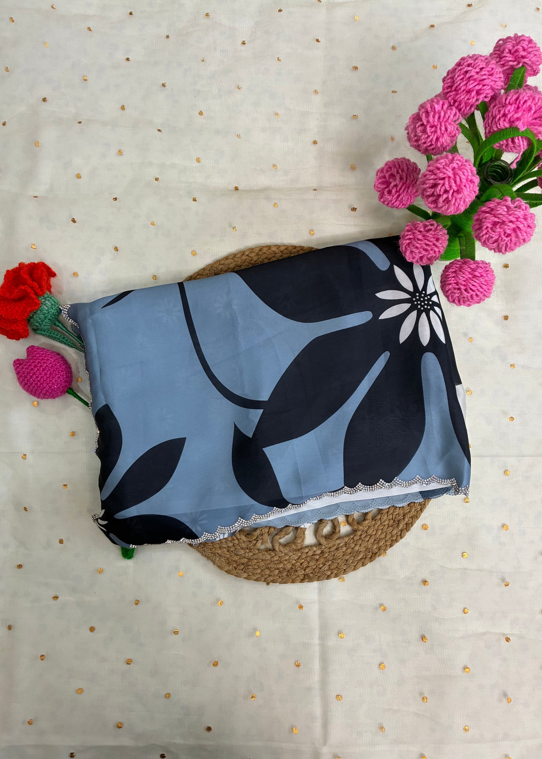 Blue fabric with black floral pattern on a textured surface with flowers.