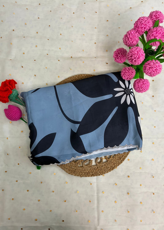 Blue fabric with black floral pattern on a textured surface with flowers.