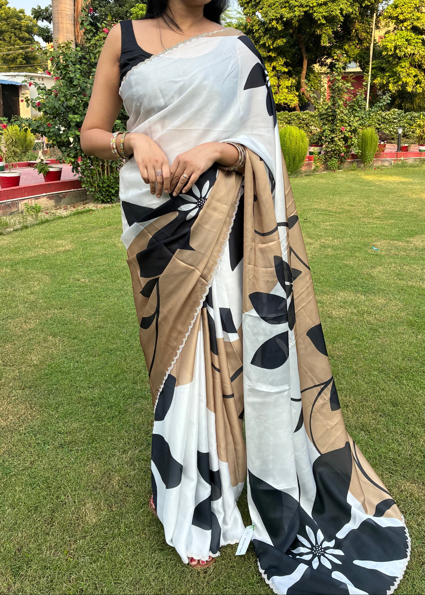 Woman wearing a black and white saree with a garden background