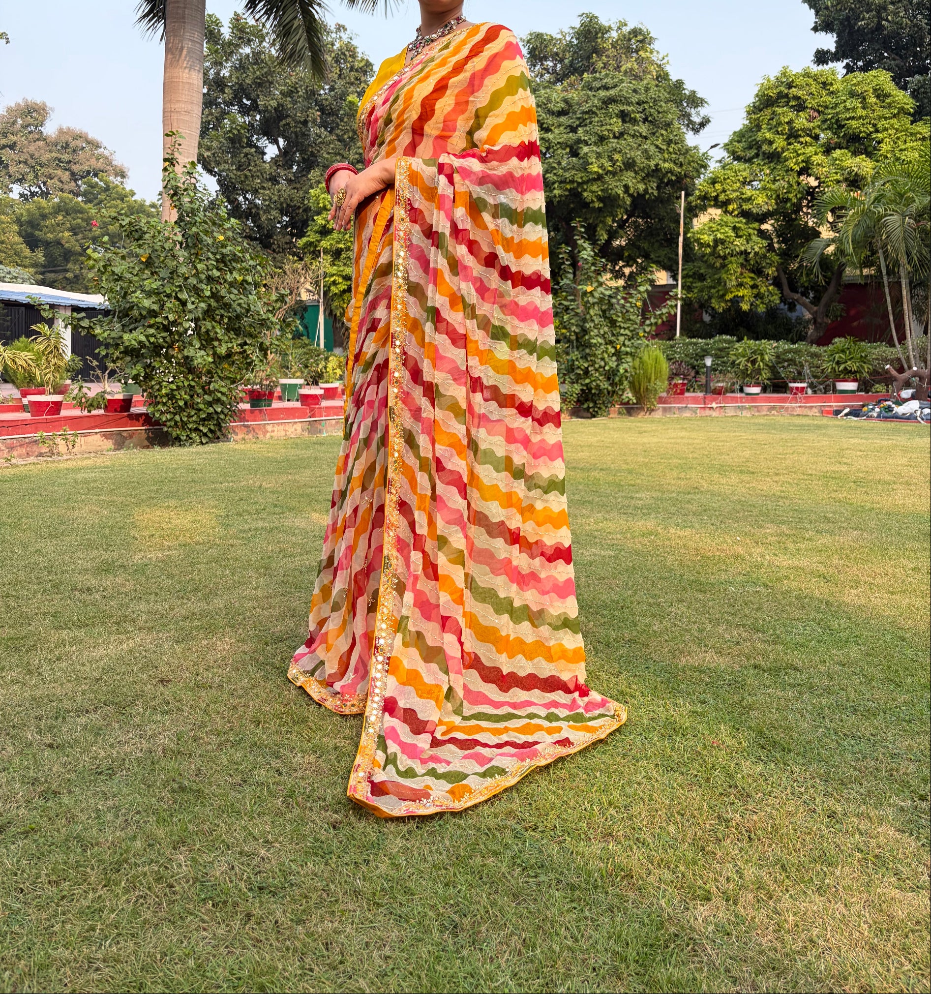 Person holding a colorful striped fabric in an outdoor setting with trees and grass.