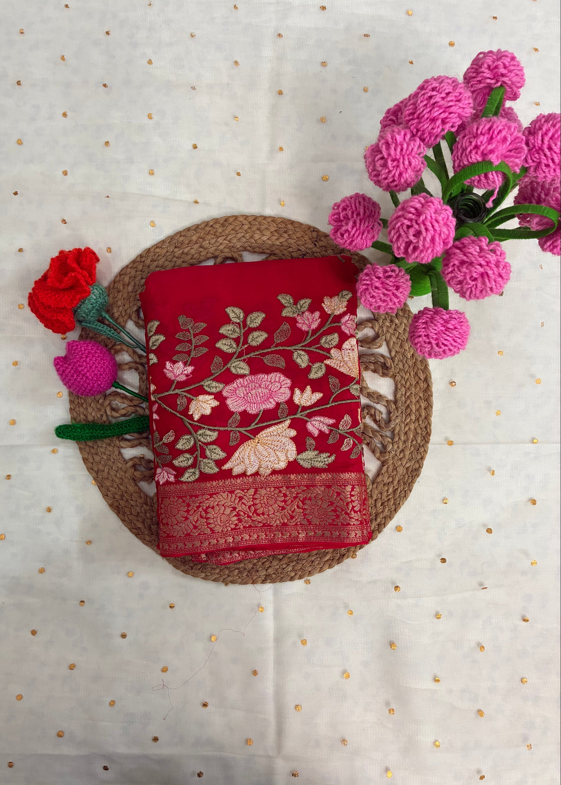 Red embroidered fabric on a woven basket with pink flowers on a light background