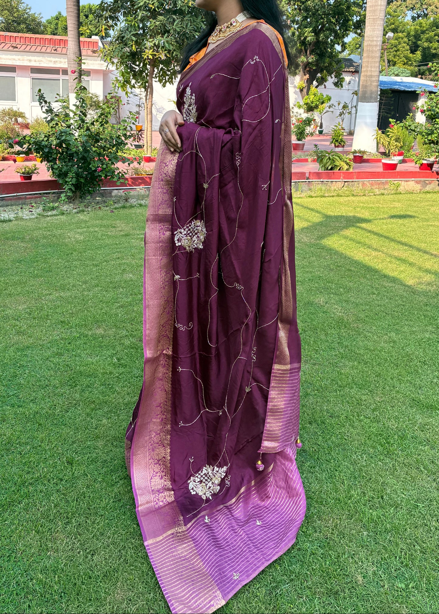 Person wearing a purple saree with a scenic background