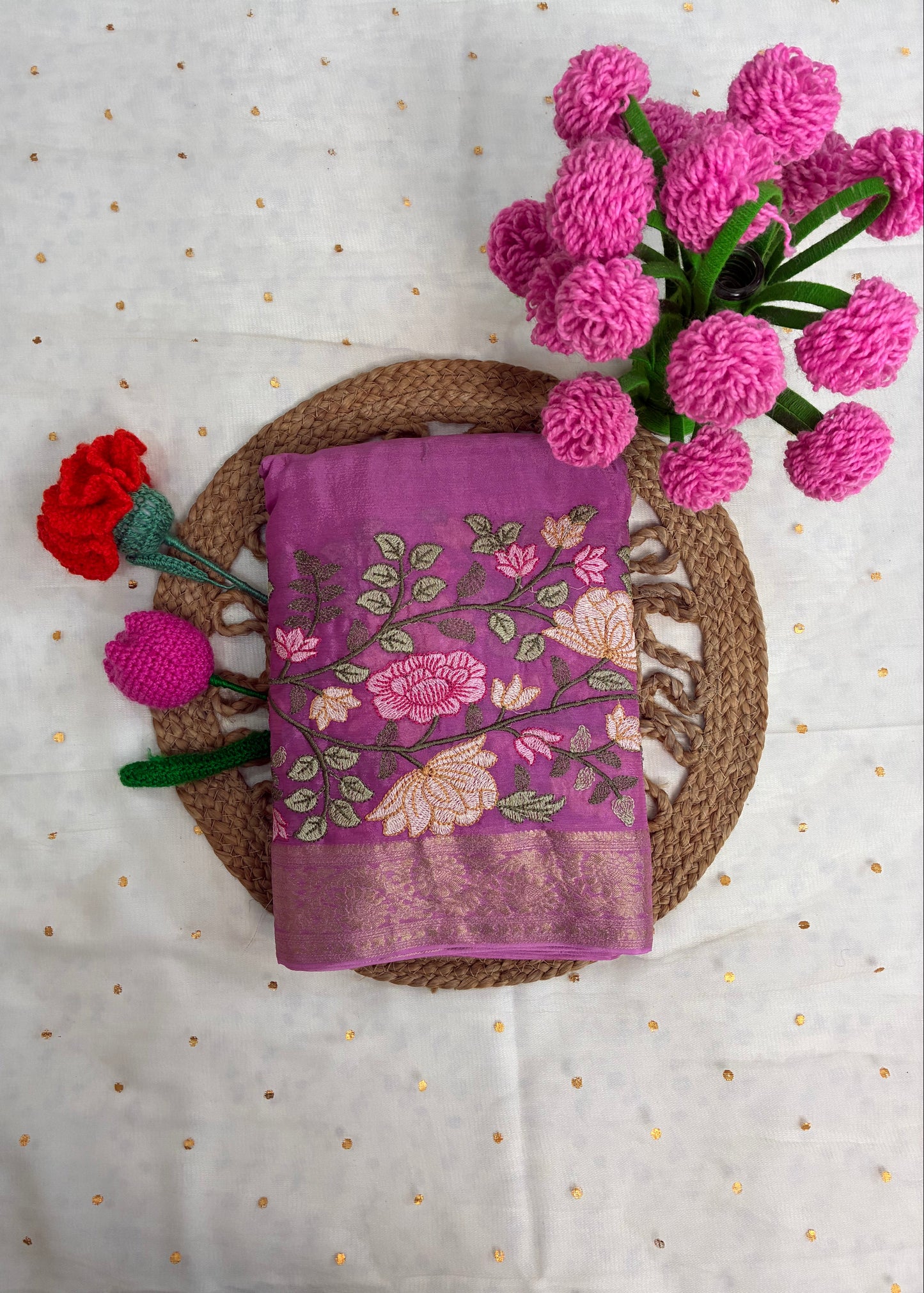 Purple fabric with floral embroidery on a textured surface with pink flowers.