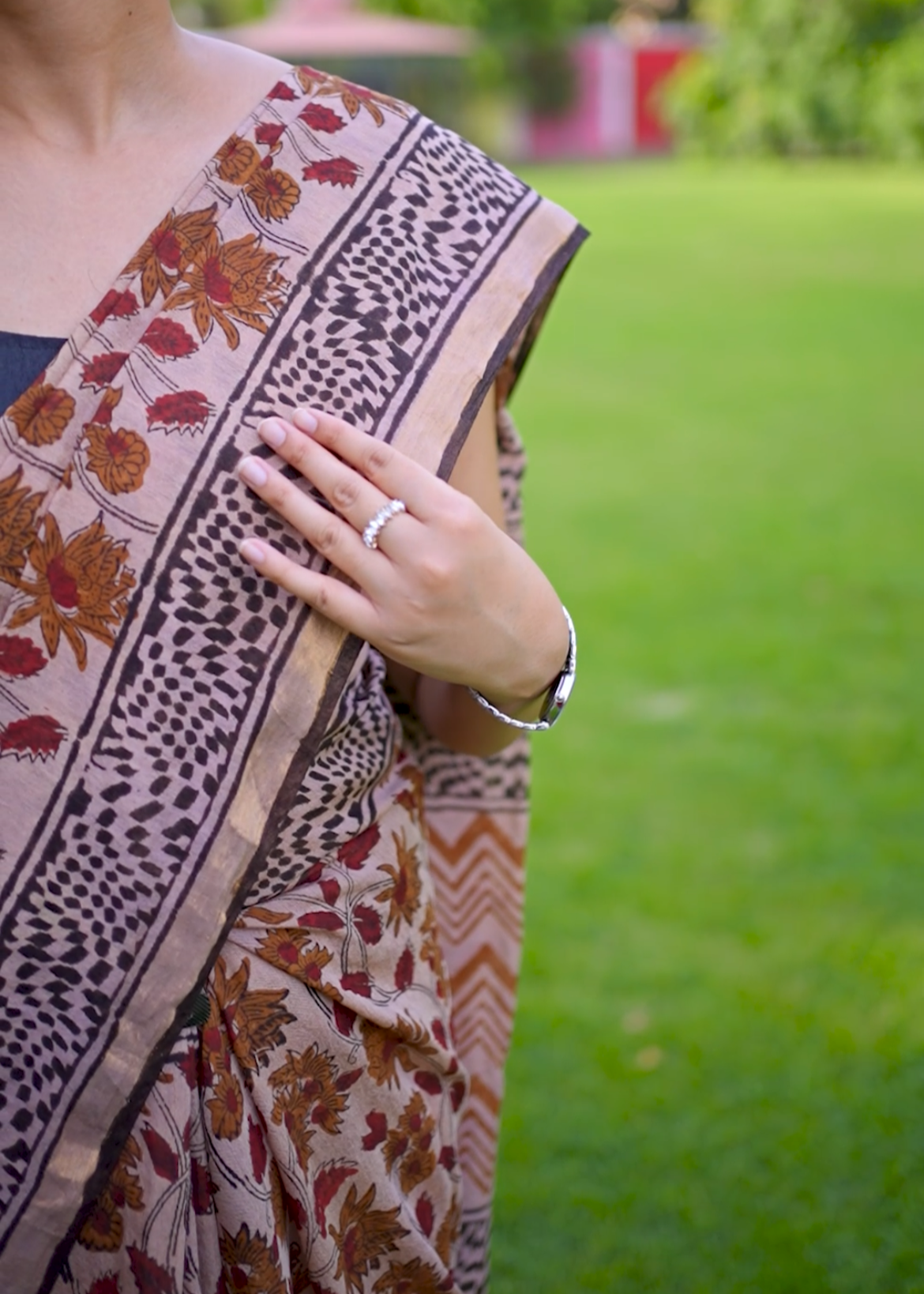 Person wearing a patterned saree with a blurred green background