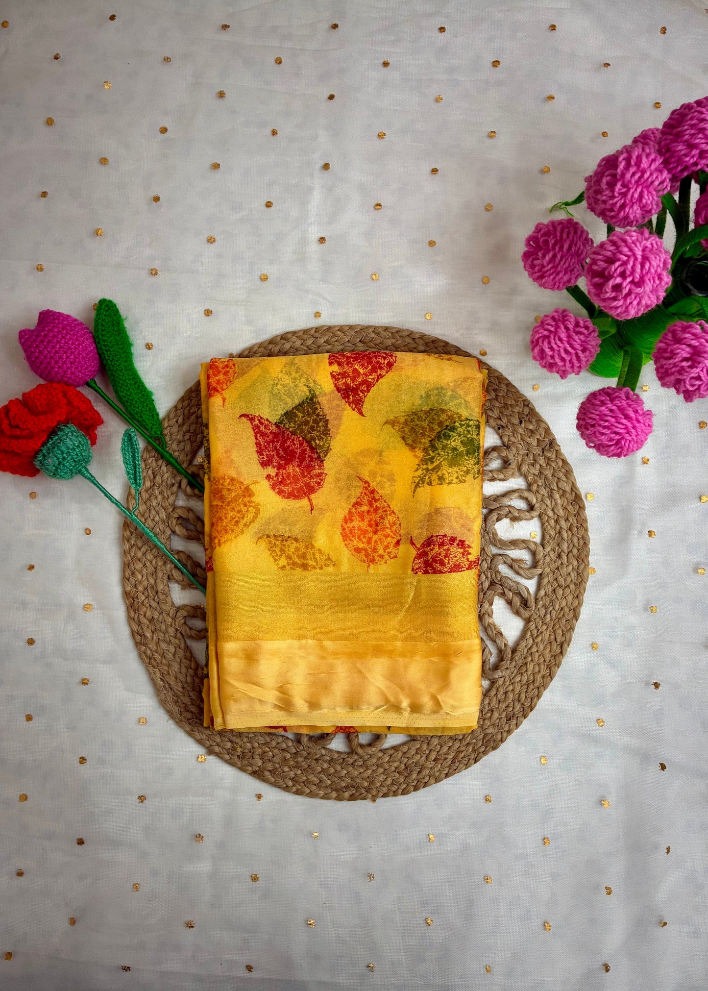 Yellow fabric with leaf pattern on a woven mat with flowers on a polka dot background