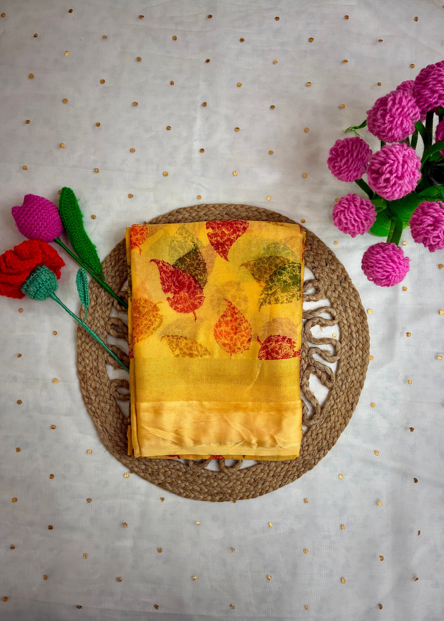 Yellow fabric with leaf pattern on a woven mat with flowers on a polka dot background