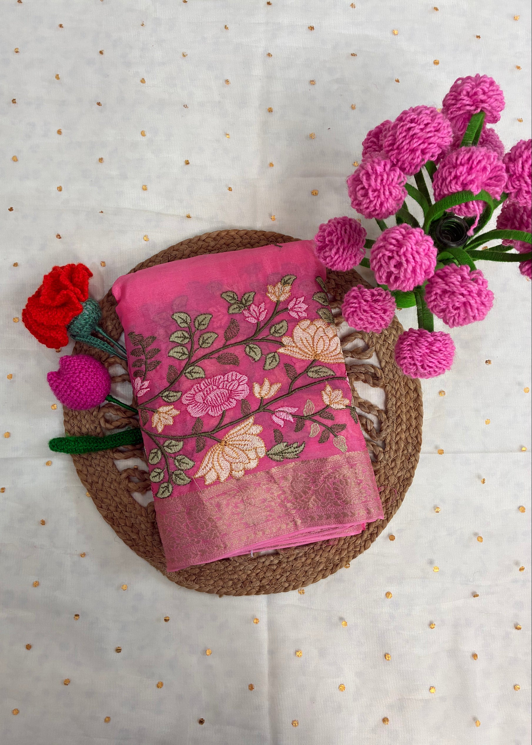 Pink floral fabric on a woven mat with decorative flowers on a polka dot background