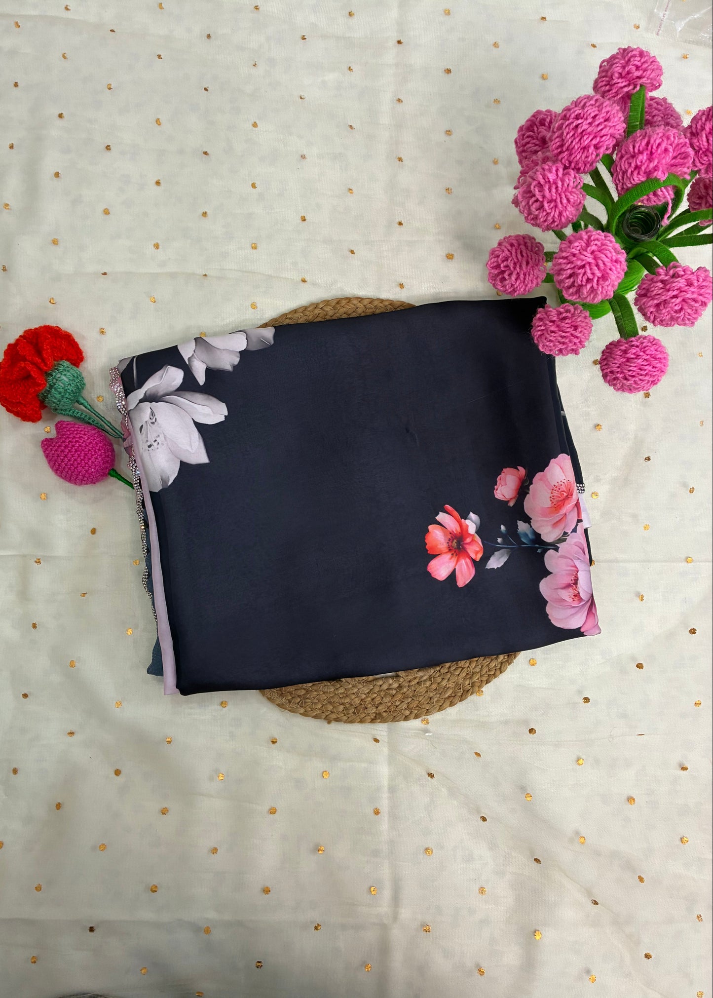 Black fabric with floral patterns on a textured surface with pink flowers.
