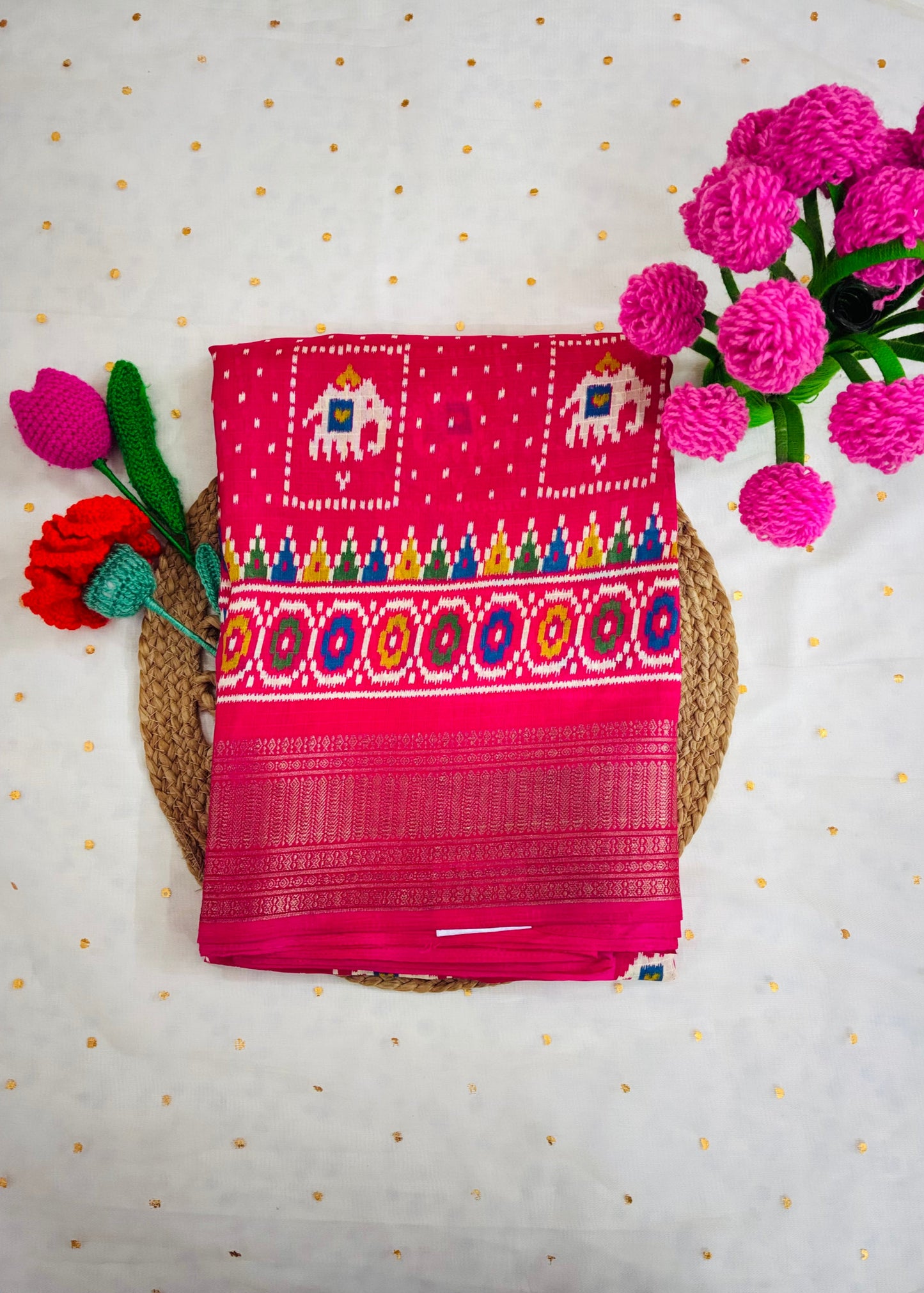 Pink embroidered fabric with colorful patterns on a textured surface with flowers.