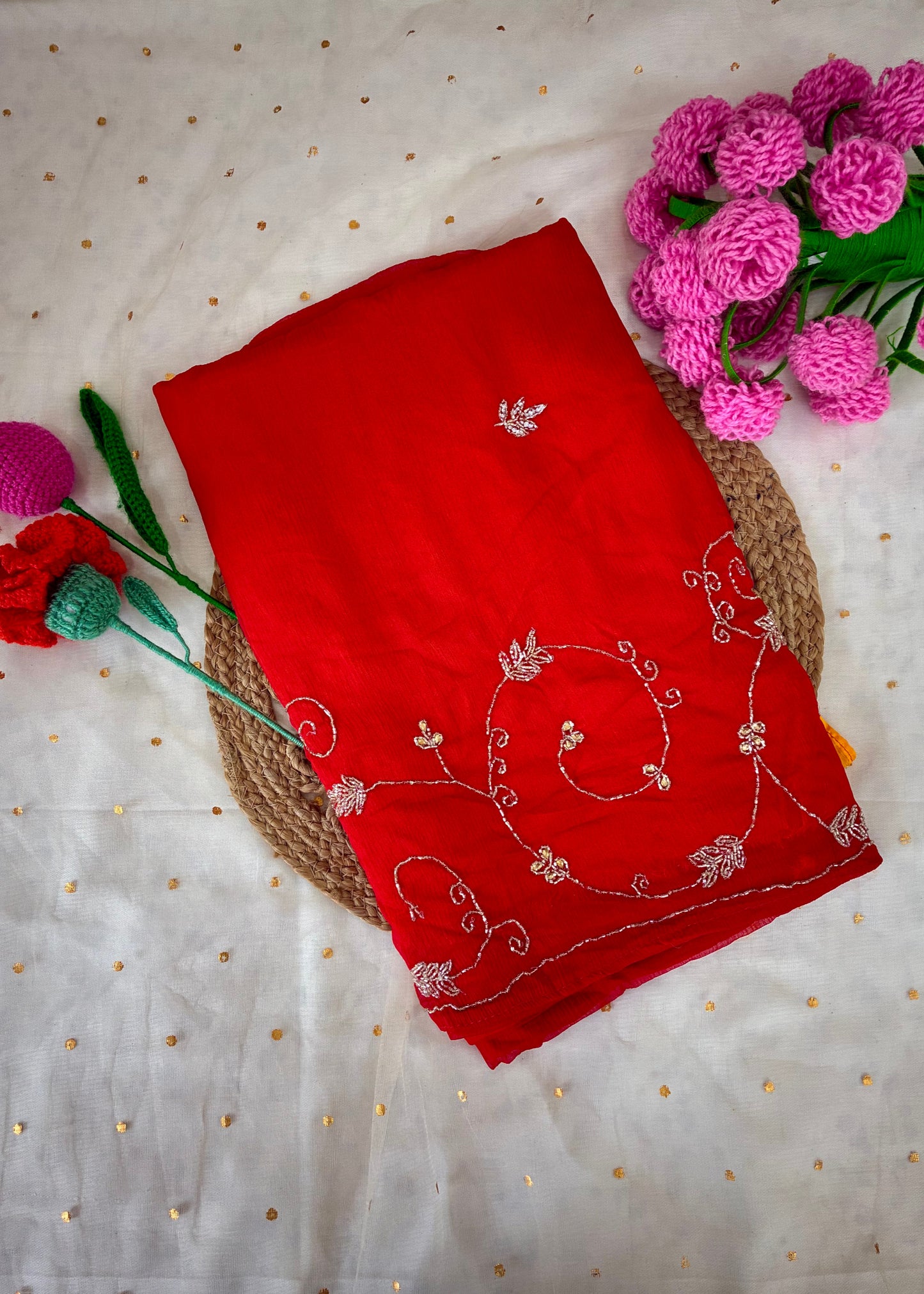 Red embroidered fabric on a textured surface with pink flowers.