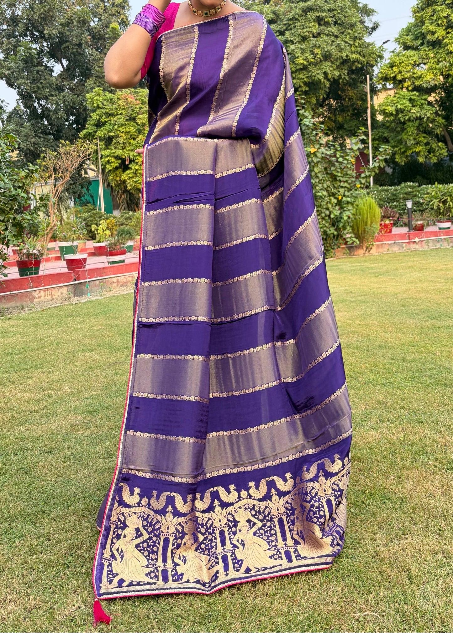 Woman wearing a purple and gray striped saree with a garden background