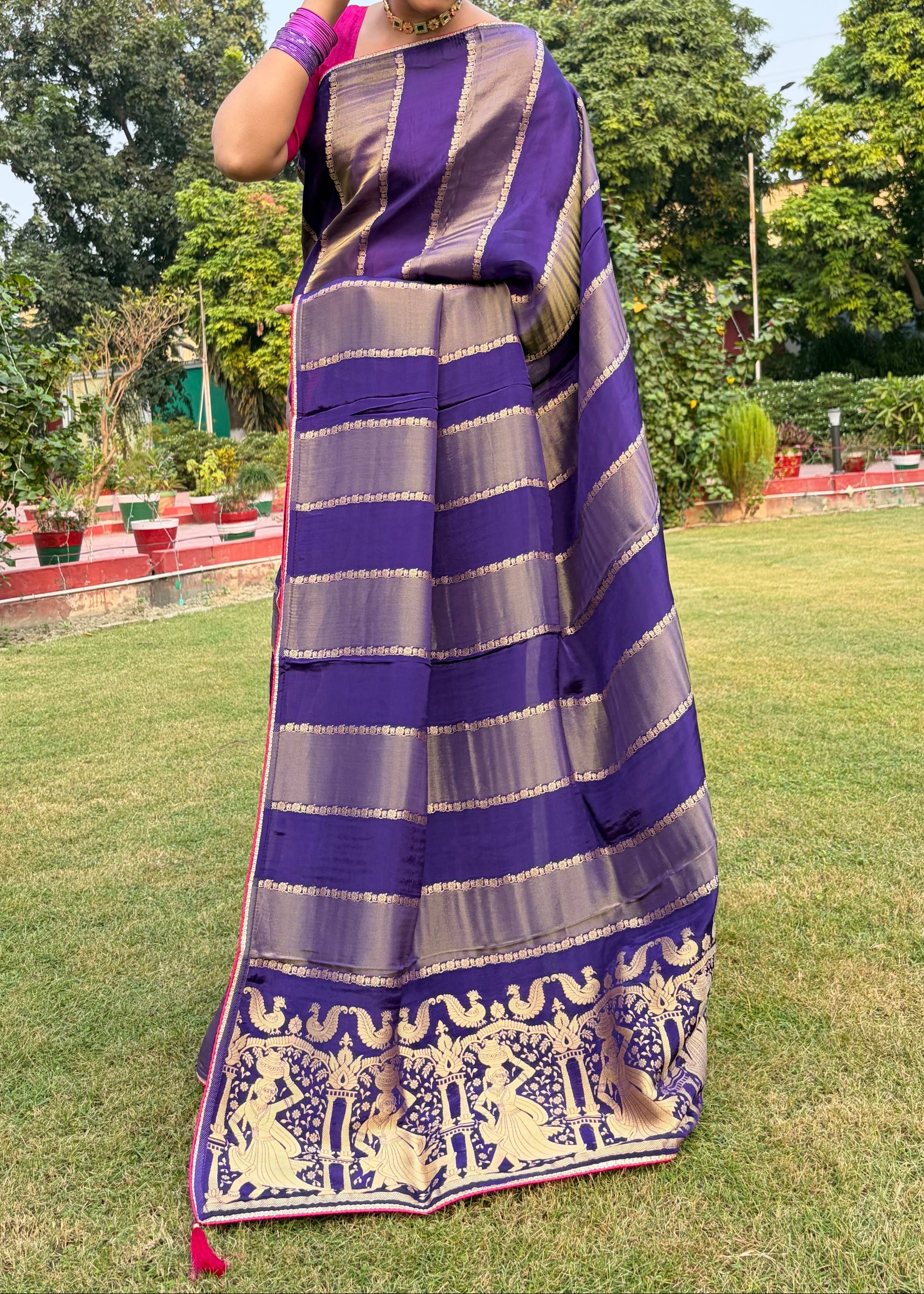Woman wearing a purple and gray striped saree with a garden background