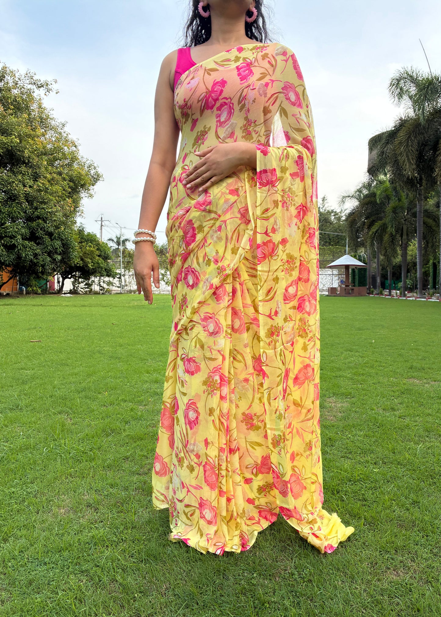 Person wearing a colorful floral dress standing on grass with trees in the background