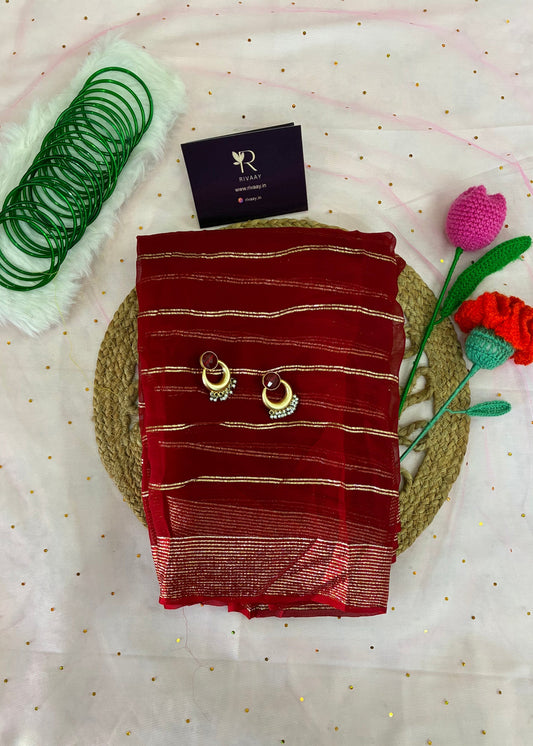 Red saree with gold patterns on a white fabric background