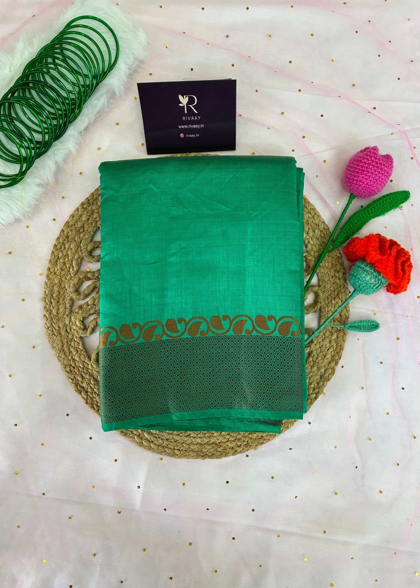 Green saree with gold border on a white fabric background