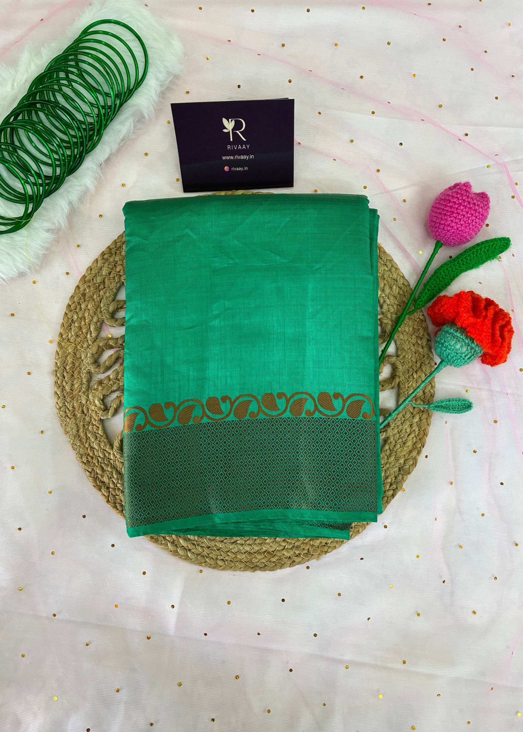 Green saree with gold border on a white fabric background