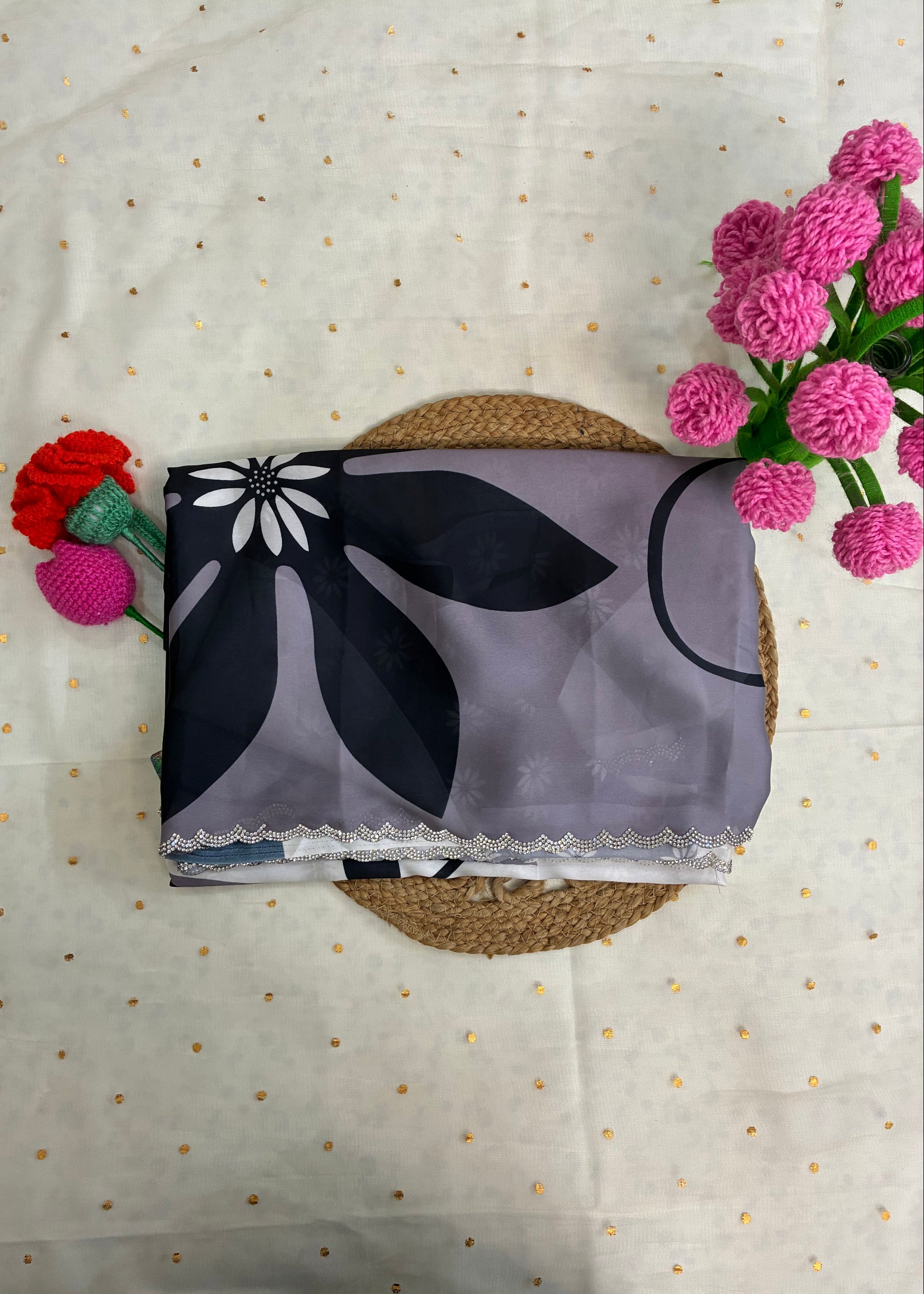 Floral-patterned fabric on a textured surface with pink flowers and a red flower arrangement.