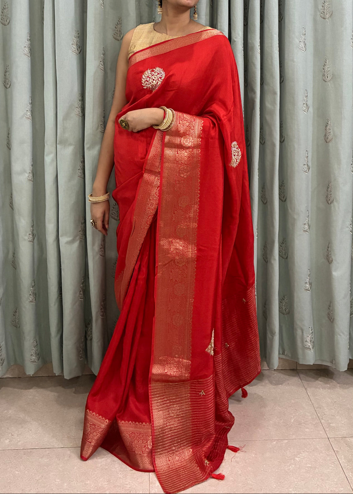 Person wearing a red saree standing in front of corrugated metal sheets.
