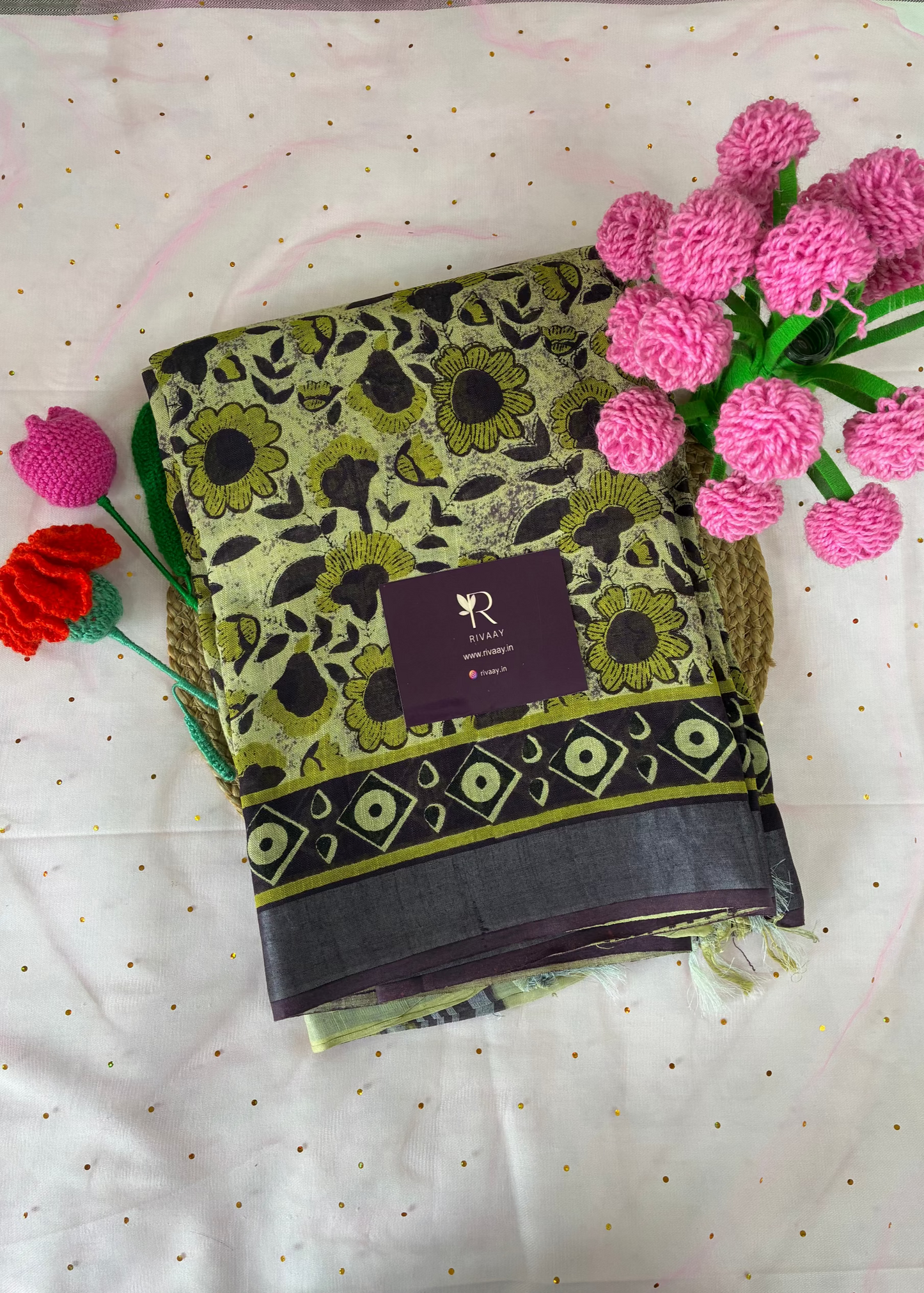 Green and black patterned fabric with a brand label on a white background with green flowers.